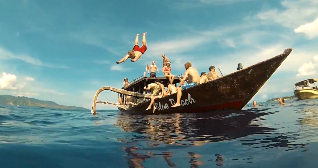 Bali Boat Trip Man diving from a traditional Indonesian boat