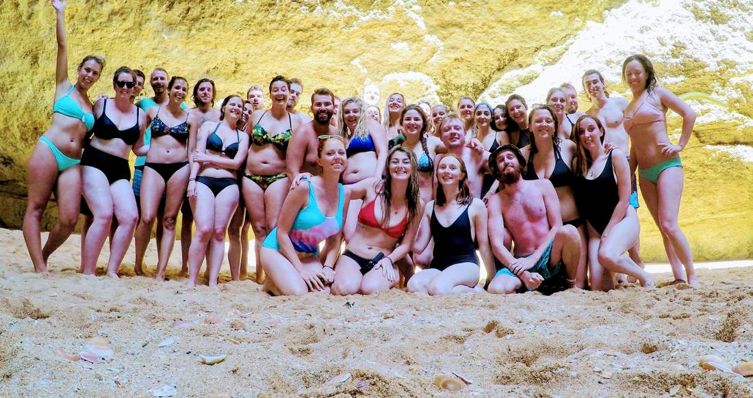 Beach Algarve A group of happy people sit along a large stone wall on a seashell lined beach