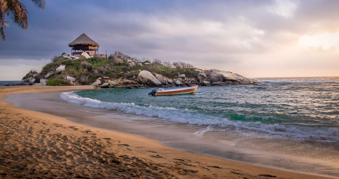 Beach Colombia A boat floats in a small bay along a beautiful beach at sunset