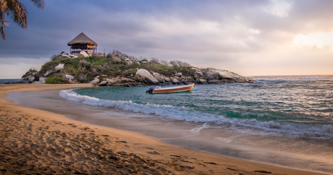 Beach Colombia A boat floats in a small bay along a beautiful beach at sunset