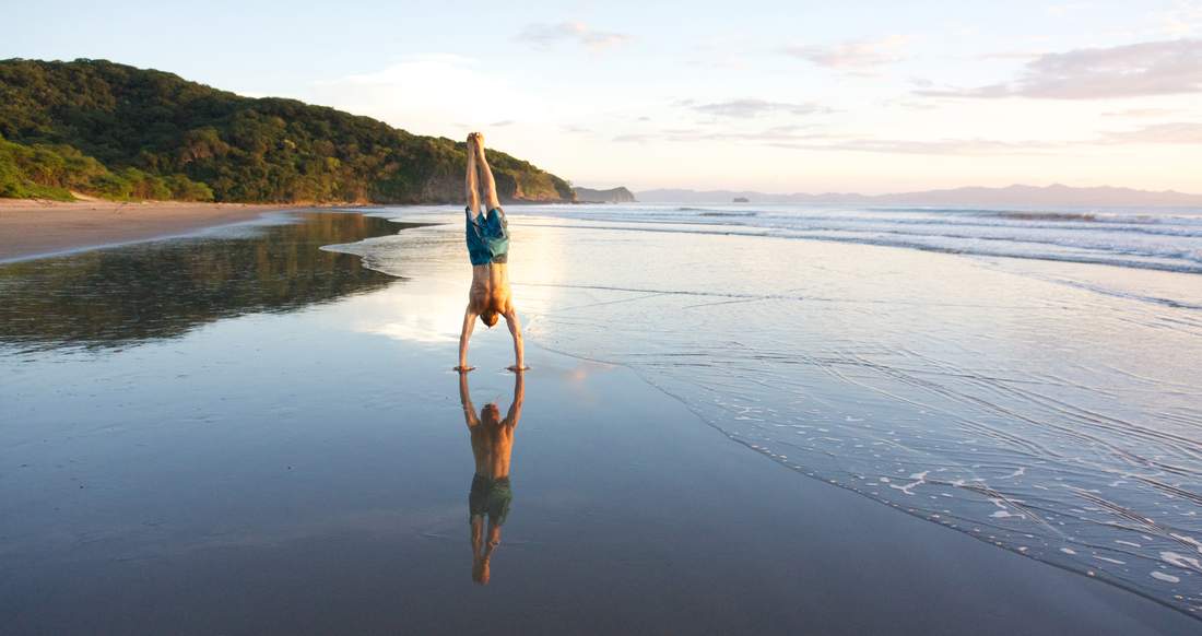 Beach Escemeca A man does a hand stand on a beautiful beach