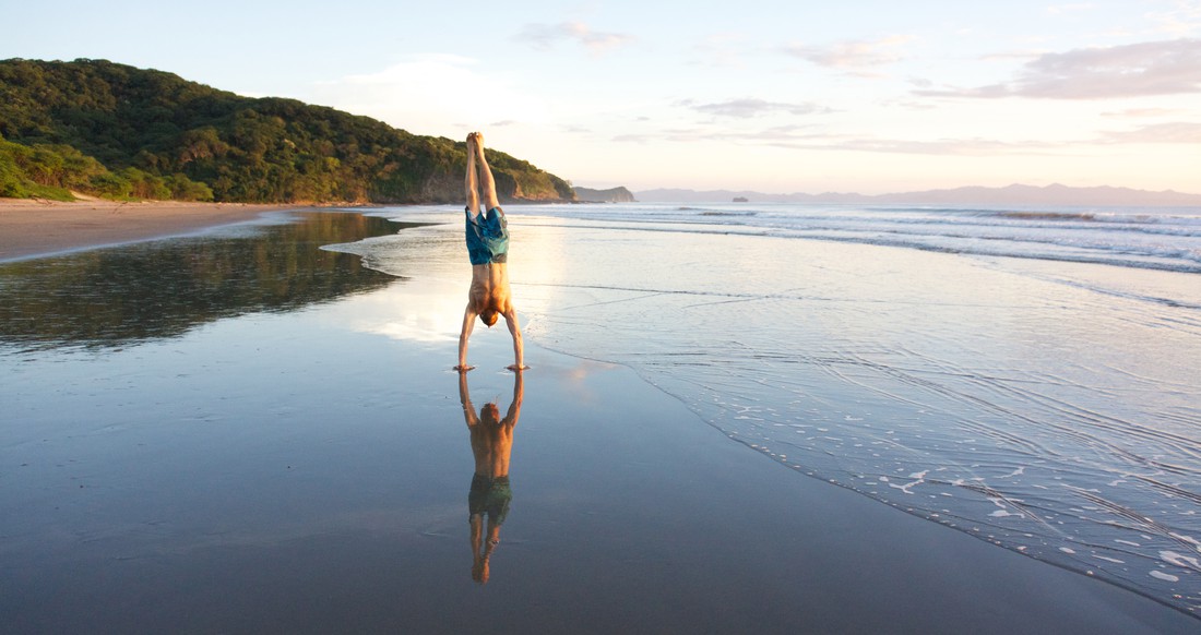 Beach Escemeca A man does a hand stand on a beautiful beach