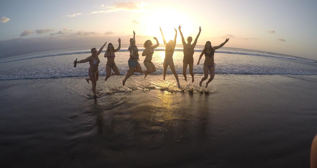 Beach Nicaragua A group of people do a jumping pose on a beach at sunset