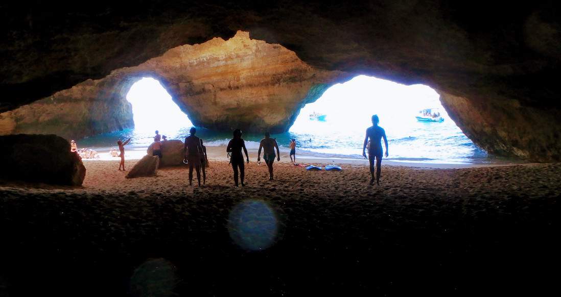 Beaches Portugal silhouettes of people standing inside a cave look at the ocean through two large rock openings