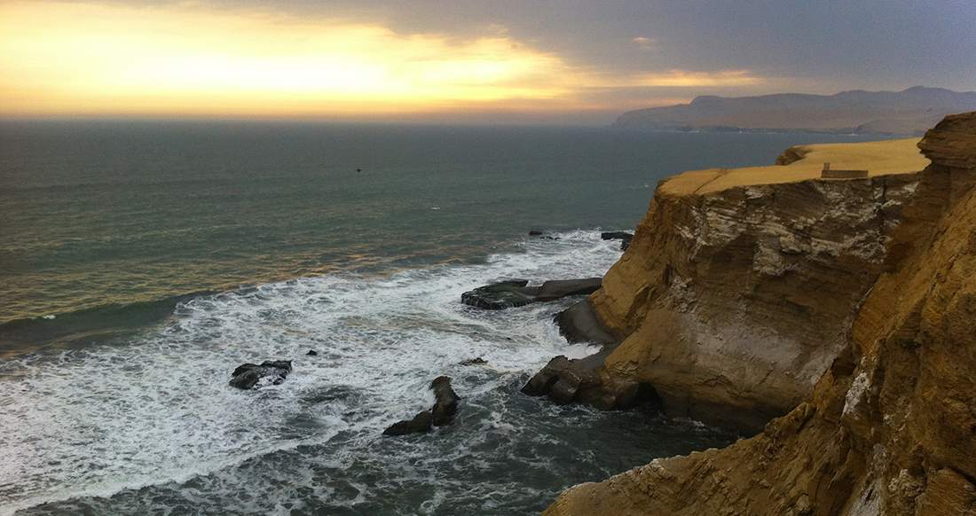 Coast line Peru Waves crash into a rocky coastline at sunset