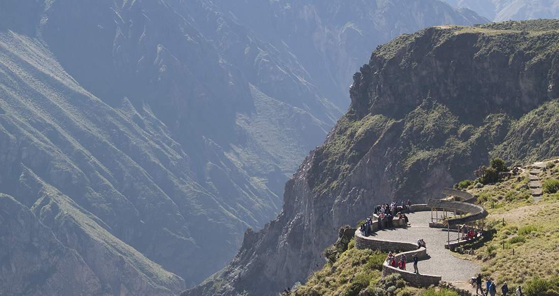 Colca Canyon Peru A group of people stand on a narrow winding viewpoint overlooking an epic mountain range
