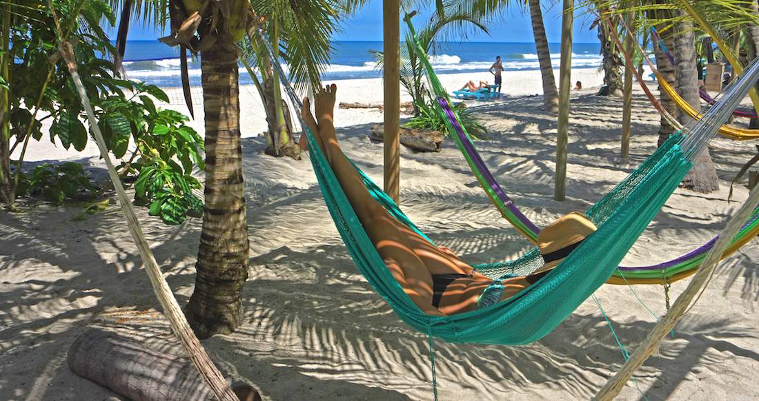 Beach Hammock A women relaxes in a colourful hammock along a palm tree lined beach