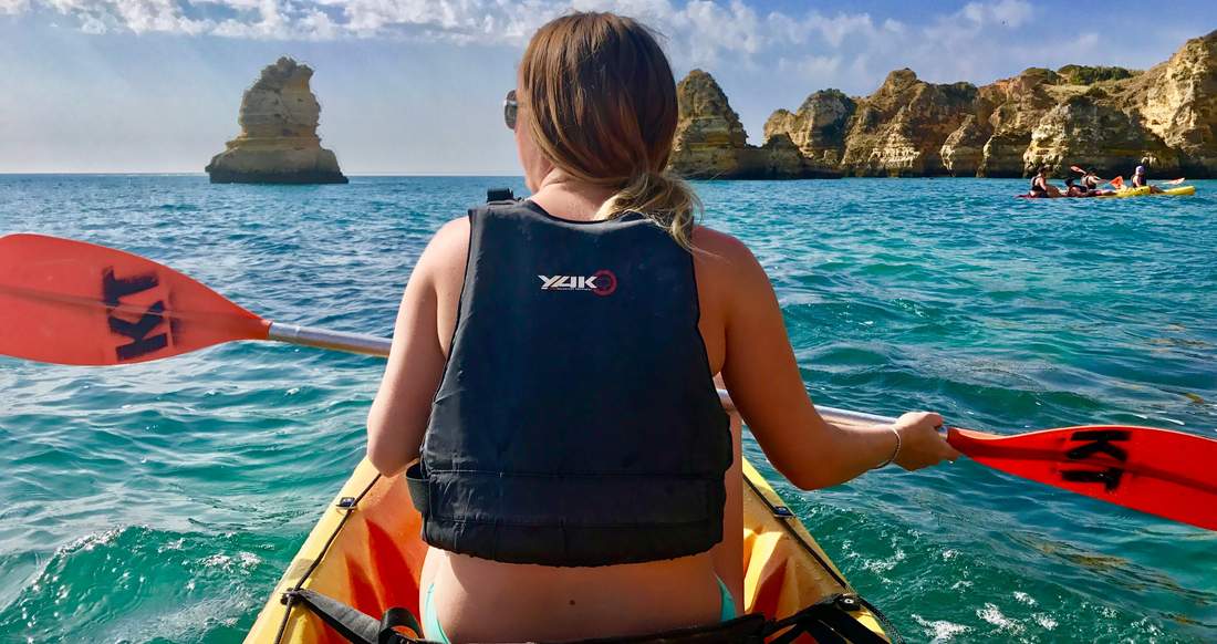 Kayaking Lagos A girl Kayaks on crystal blue waters towards rock formations in the ocean