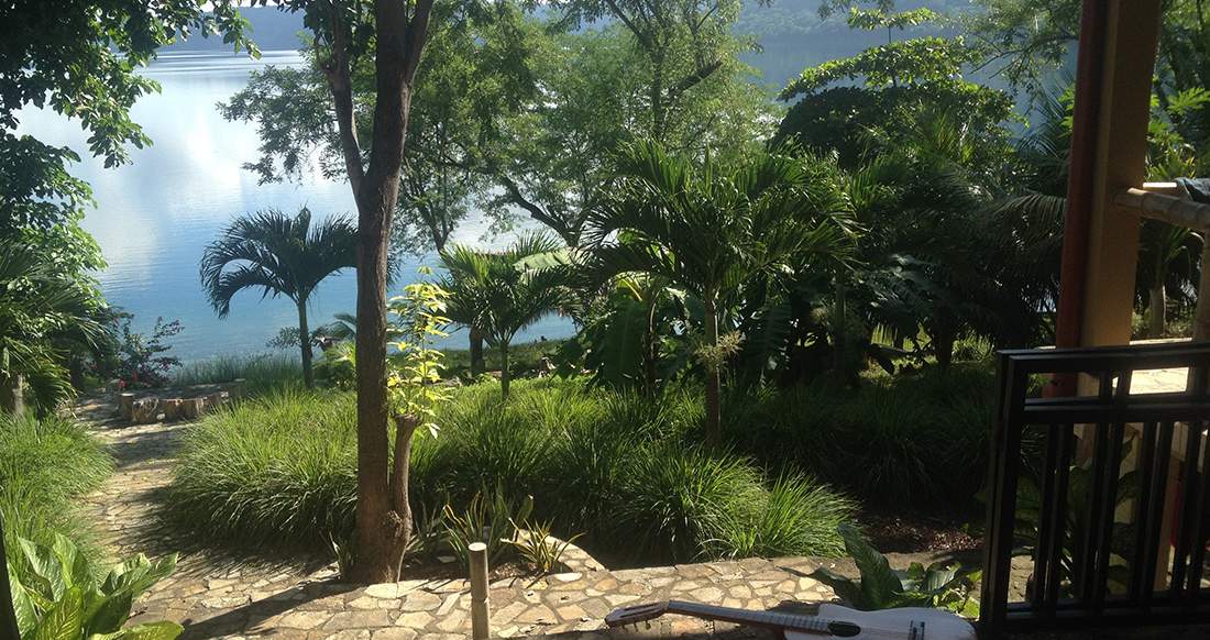 Laguna de Apoyo A guitar rests on the steps of a bungalow with a view of lush greenery surrounding a crater lake