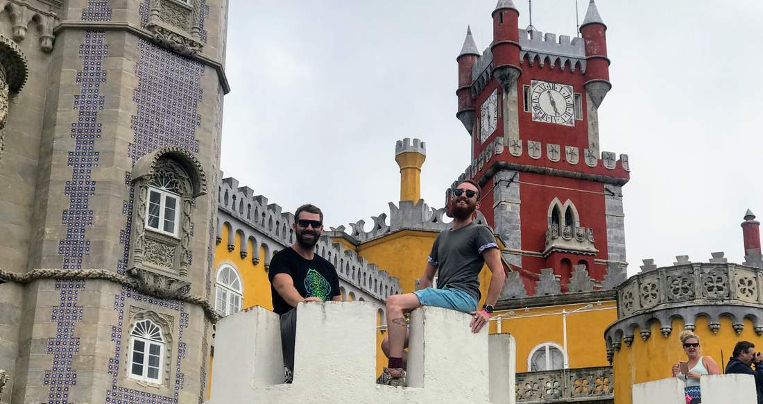 Pena Palace Sintra Two smiling men wearing sunglasses sit in a small silo in a colourful palace