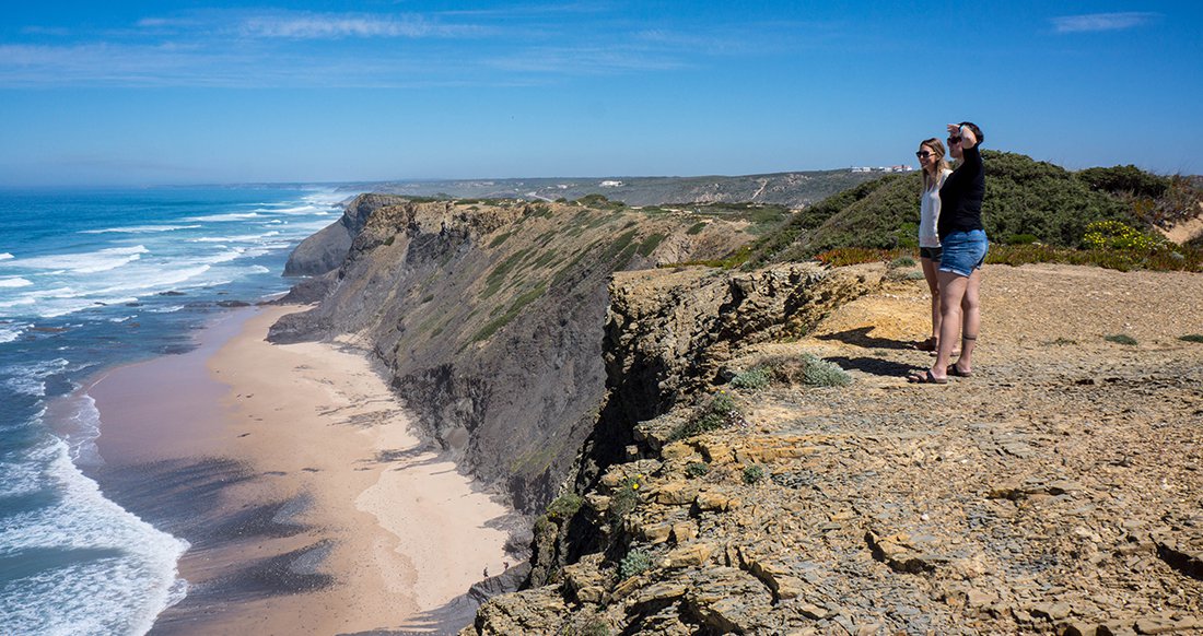Portugal Coast Cliffs Two women look out over a massive cliff oceanside