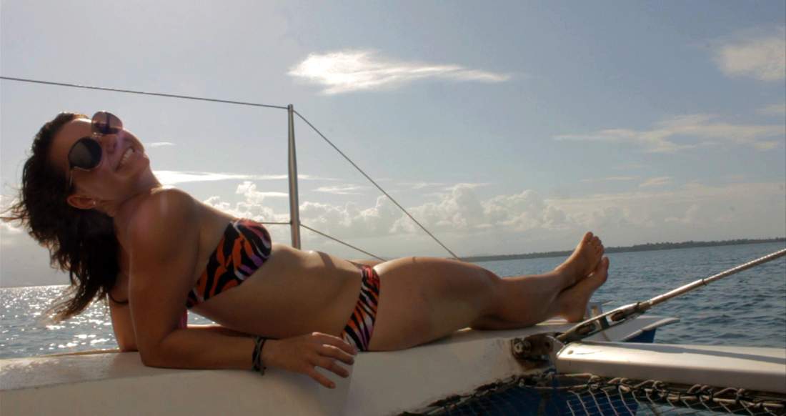 Sailing Bocas Del Toro Panama A smiling girl in sunglasses lounges on the front of a sail boat