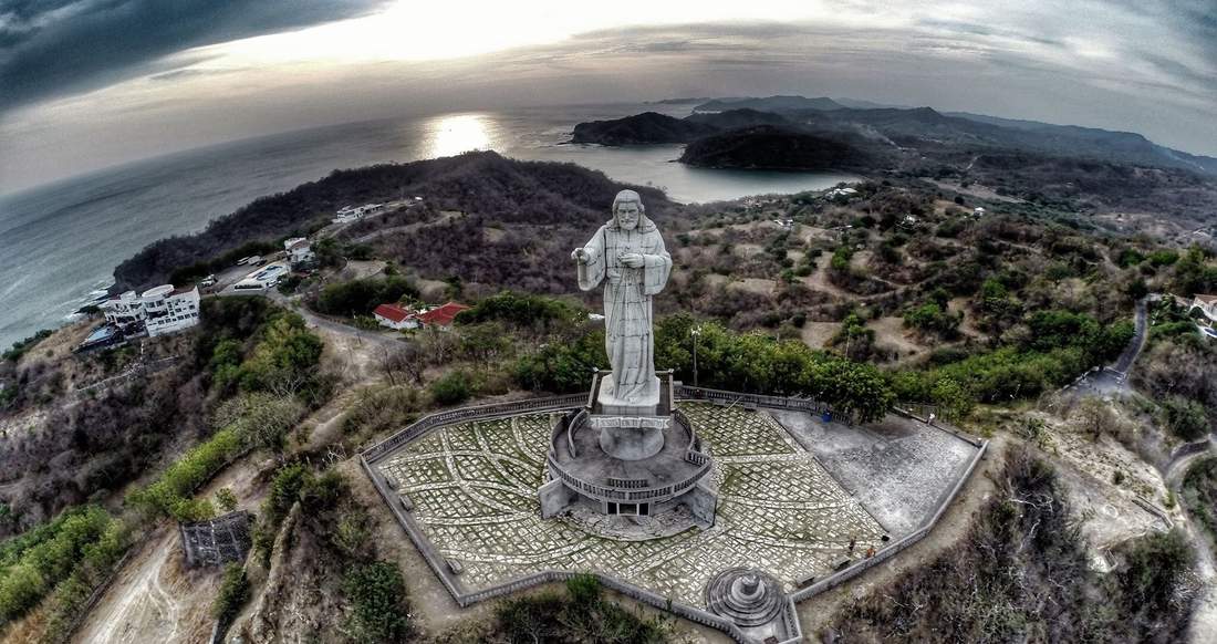 San Juan del Sur Nicaragua Aerial view of a large Jesus statue on a mountain with a view of the coastline and surrounding town