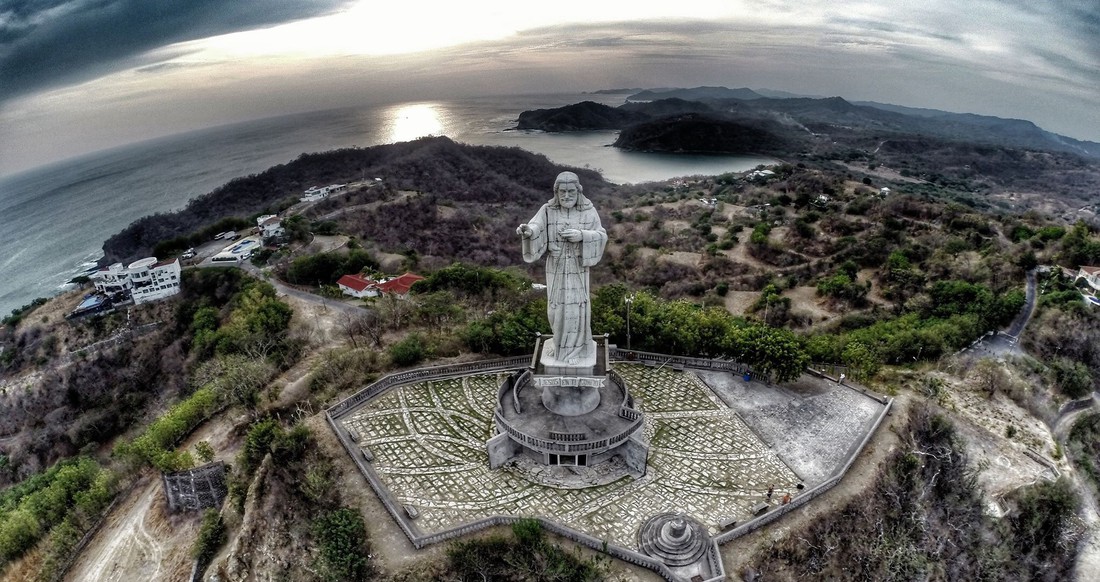 San Juan del Sur Nicaragua Aerial view of a large Jesus statue on a mountain with a view of the coastline and surrounding town