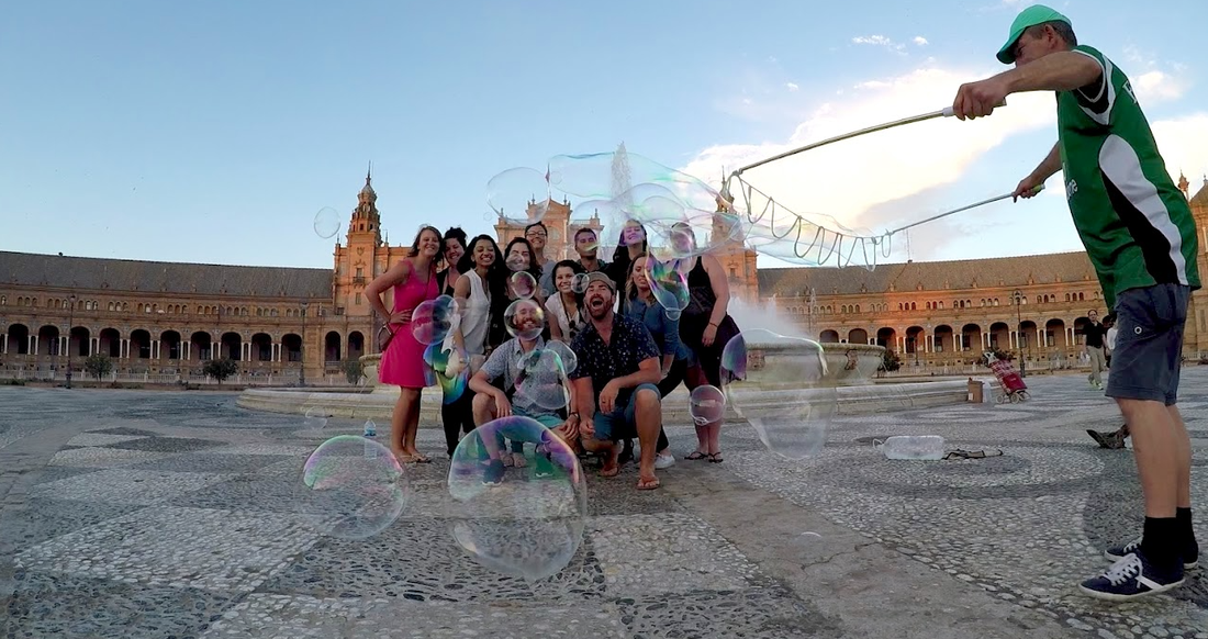 Seville Spain A bubble blower blows large bubbles in front of a group in a large square