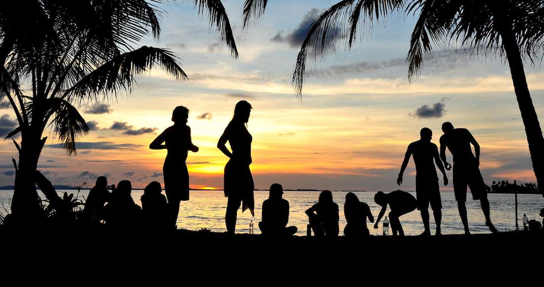 Sunset Beach Silhouettes of people and palm trees on a beach at sunset