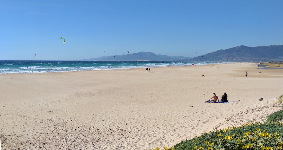Tarifa Beach Two small figures sit on a huge empty beach