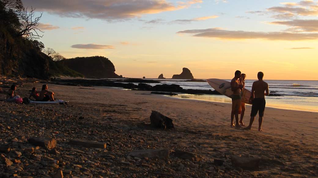 Sunset Surfs group of travelers on the beach with their surfboards while the sun sets in Nicaragua