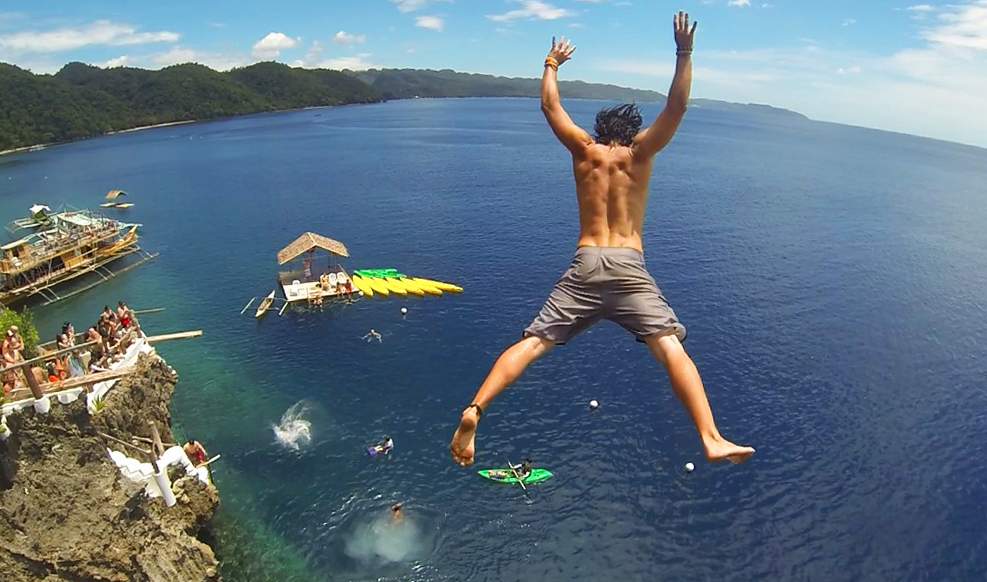 Cliff jumping in the Philippines Traveler cliff jumping into the ocean in the Philippines