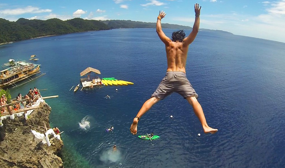 Cliff jumping in the Philippines Traveler cliff jumping into the ocean in the Philippines