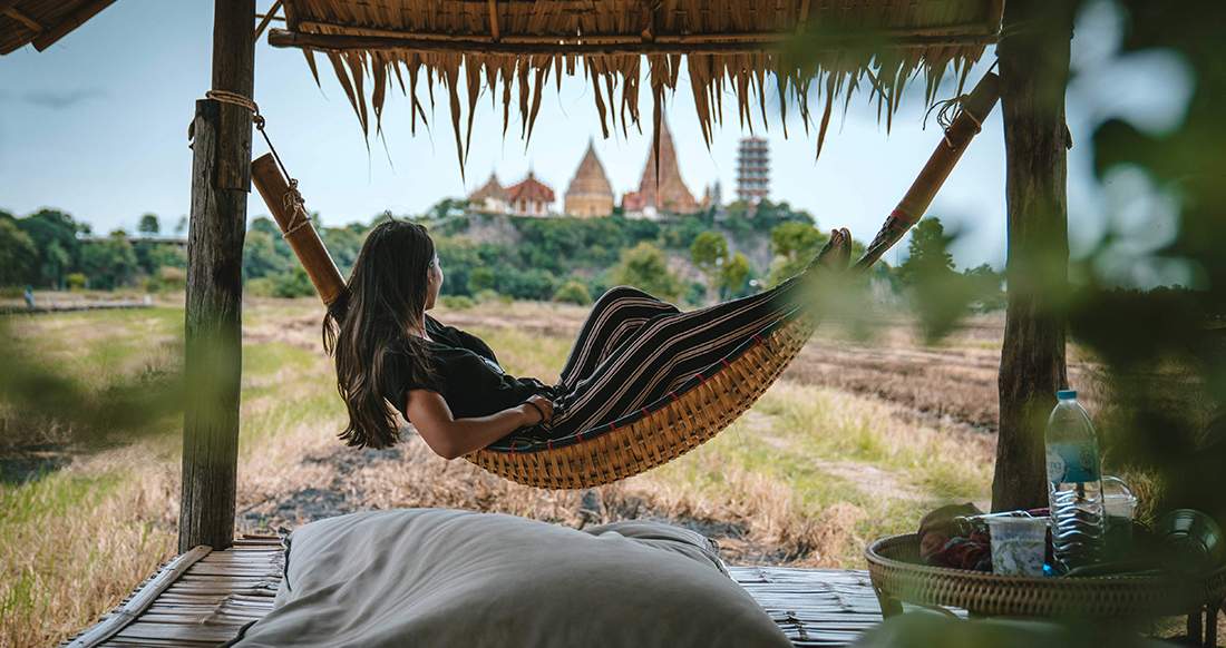 Girl in a hammock in Thailand Girl in a hammock with a view of a temple in Thailand
