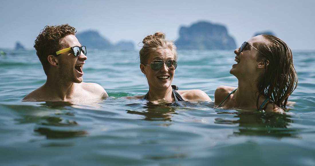 People in the ocean laughing in Thailand Three people laughing in the ocean in Thailand
