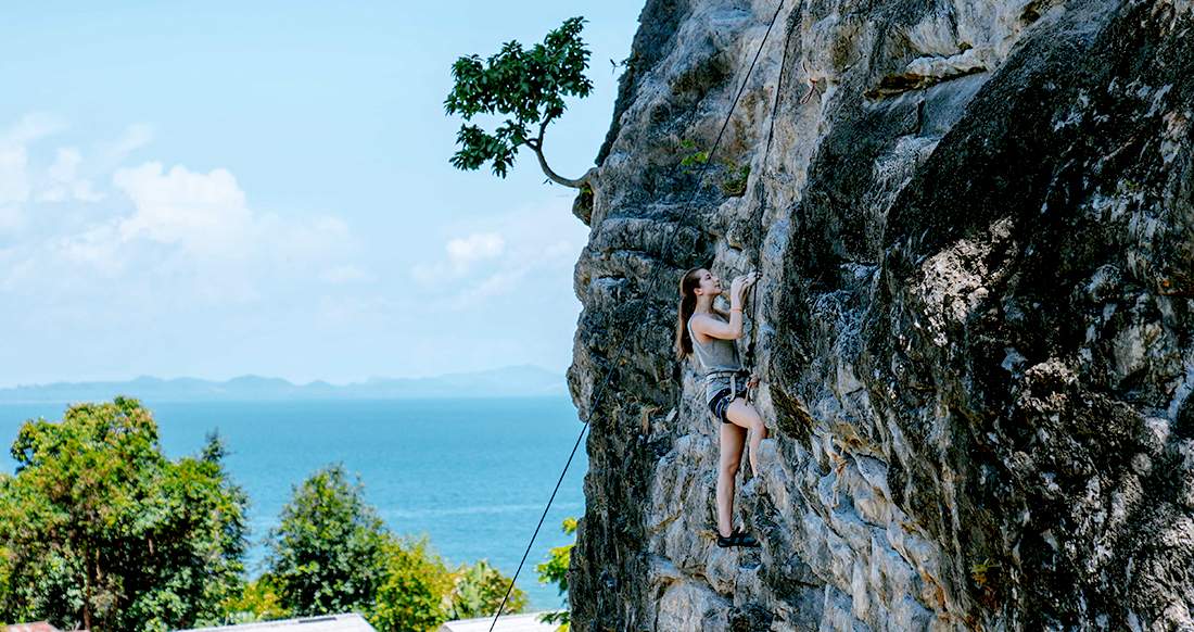 Rock climbing in Railay Thailand Traveler climbing a rock face in Railay, Thailand
