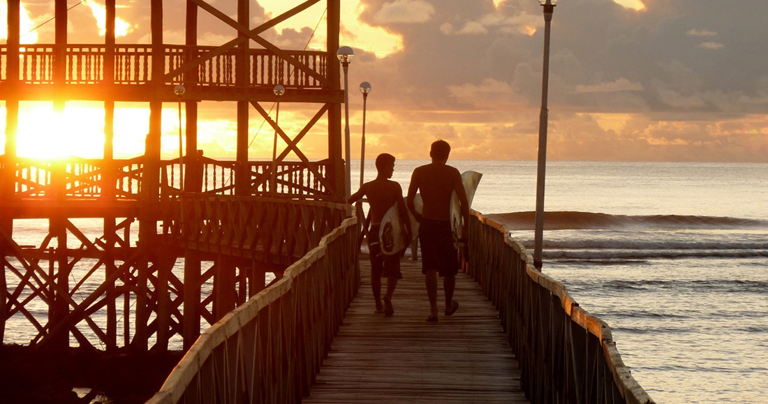 Sunset in Siargao Philippines Two travelers walking along a boardwalk while the sun sets in the Philippines