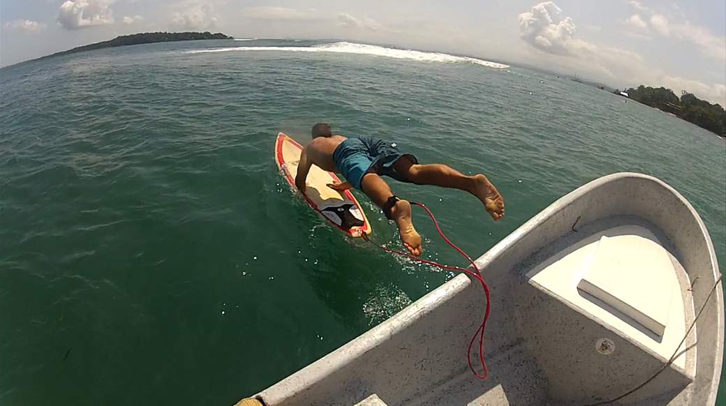 surf dude jumping into the ocean from a boat with a surfboard in panama