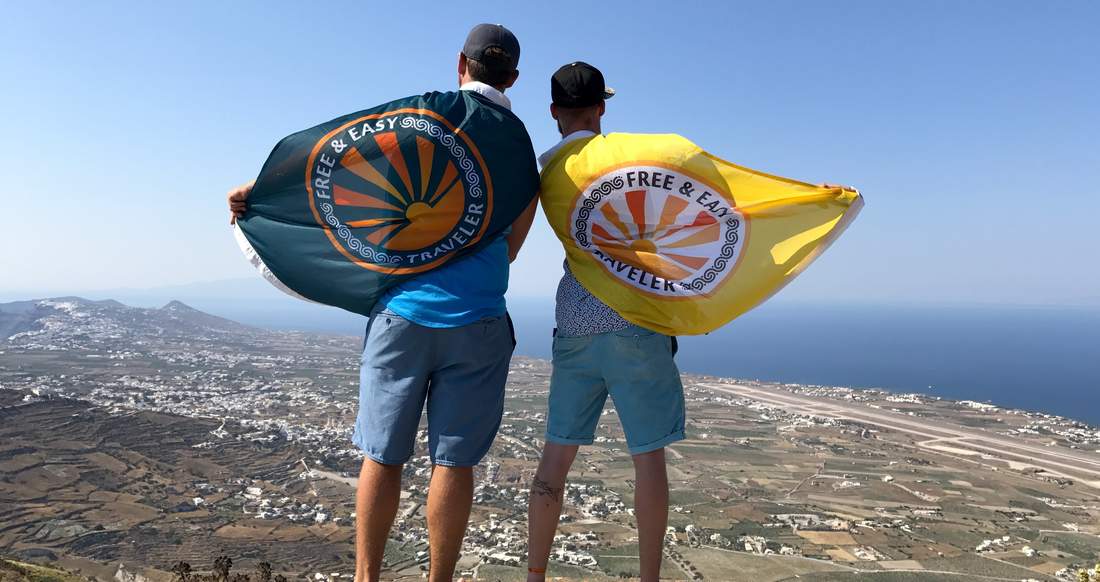 Viewpoint two guys looking at the view with flags on their backs in Greece