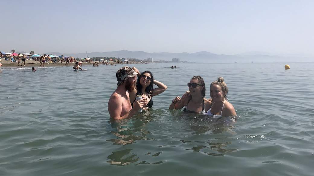 ocean beers group of travelers standing in the water enjoying some drinks in Spain