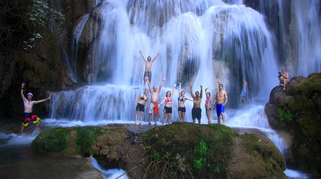 waterfall A group of travelers standing under a waterfall in Laos