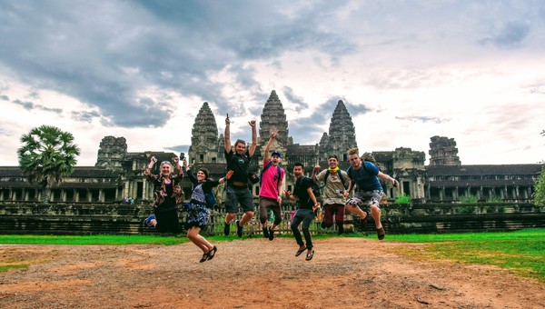 A group of travelers jumping with joy in front of Angkor Wat.