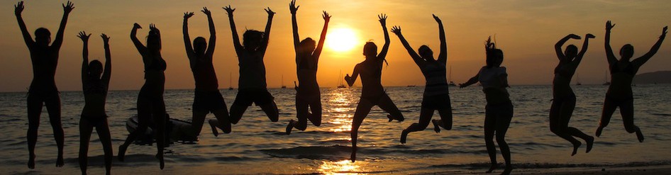 a group of happy people jumping holding hands in front of a beach